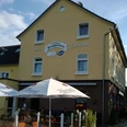 Ein gelbes Gebäude mit der Aufschrift "Knappmann Hotel Restaurant" und einem sonnigen Biergarten.