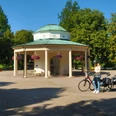 Eine Radfahrerin stoppt an einem Pavillon in einem Park, um ihre Route auf der Landkarte zu überprüfen.