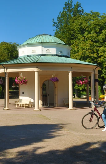Radfahren Horn-Bad Meinberg Eine Radfahrerin stoppt an einem Pavillon in einem Park, um ihre Route auf der Landkarte zu überprüfen.