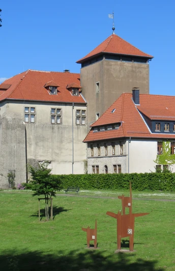 Burg Horn thront majestätisch auf einer Wiese mit rotem Ziegeldach und Umgeben von grünen Bäumen.