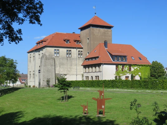 Burg Horn thront majestätisch auf einer Wiese mit rotem Ziegeldach und Umgeben von grünen Bäumen.