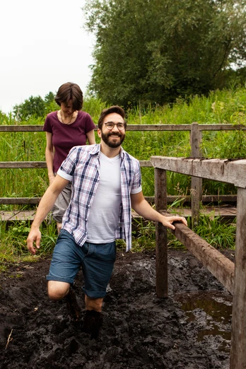 Moortretbecken Zwei Menschen nutzen ein hölzernes Moortretbecken in einer grünen, von Bäumen umgebenen Umgebung.