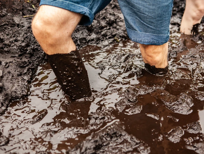 Moortretbecken Ein Mann watet knietief im braunen Moortretbecken, umgeben von dunklem, feuchtem Torf.