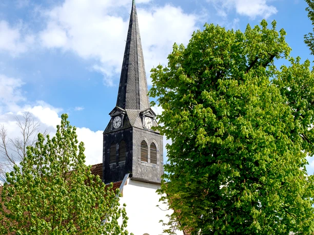 Blick auf den Glockenturm der Kirche St. Stephan bei blauem Himmel mit Wolken