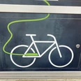 E-Bike-Ladestation Symbol eines Fahrrads mit grünem Kabel auf einer dunkelgrauen Ladestation für E-Bikes.