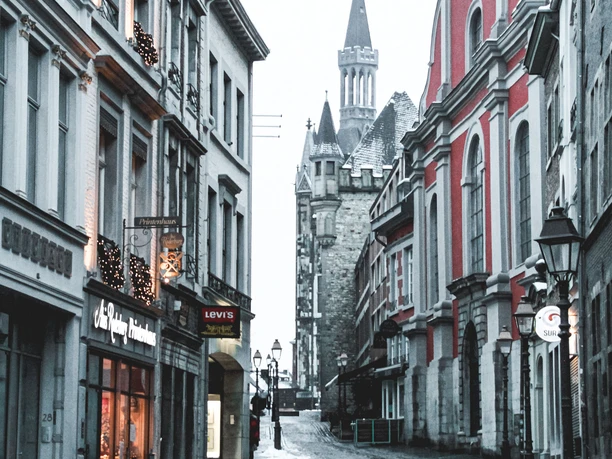 Gepflasterte Gasse zwischen bunten Häuserreihen und historischen Straßenlaternen im Winter.