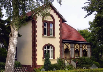 Kardinahl.jpg Historisches Backsteinhaus mit rotem Dach und verzierten Fenstern, umgeben von gepflegtem Garten.
