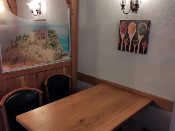 Innenansicht Pizzeria Roma 4er Tisch in der Pizzeria Roma, an der Wand hängt ein Bild