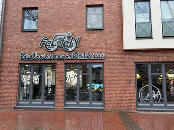 Radhaus am Rathaus Fahrradgeschäft mit roten Backsteinwänden, großen Schaufenstern und dem Schriftzug "Radhaus am Rathaus".