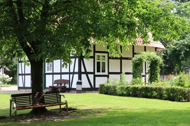 Kurpark Rothenuffeln Fachwerkhaus im Kurpark Rothenuffeln, umgeben von Bäumen und einer gepflegten Grünfläche mit Bank.