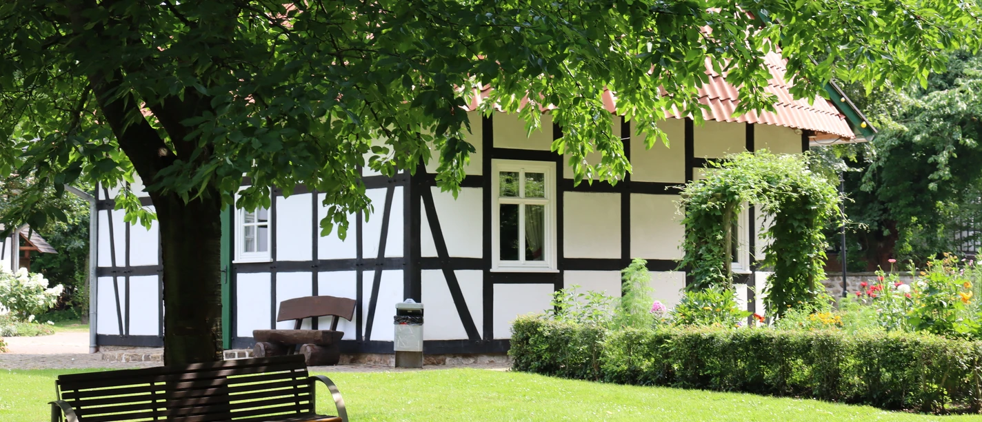 Kurpark Rothenuffeln Fachwerkhaus im Kurpark Rothenuffeln, umgeben von Bäumen und einer gepflegten Grünfläche mit Bank.