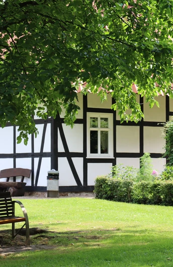 Kurpark Rothenuffeln Fachwerkhaus im Kurpark Rothenuffeln, umgeben von Bäumen und einer gepflegten Grünfläche mit Bank.