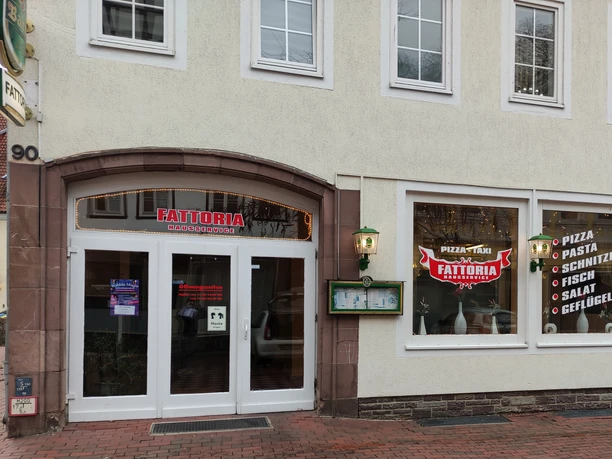 Außenansicht eines Restaurants mit großem Schaufenster, das italienische Gerichte wie Pizza und Pasta anbietet.