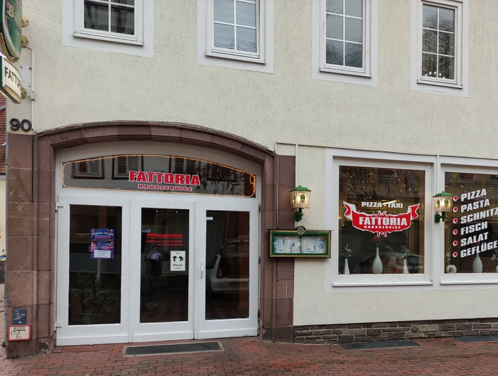 Außenansicht eines Restaurants mit großem Schaufenster, das italienische Gerichte wie Pizza und Pasta anbietet.