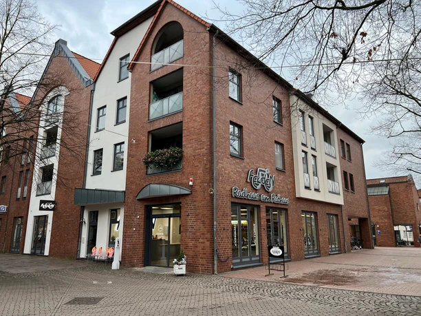 A modern brick building facade with shops on the ground floor, marked by the "Radhaus am Rathaus" sign.