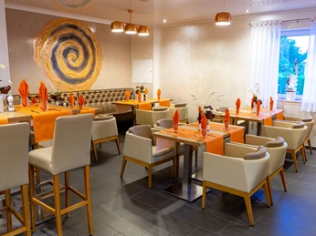 Elegantes Restaurant mit gedeckten Tischen, orangefarbenen Akzenten und einem kunstvollen Wandbild.