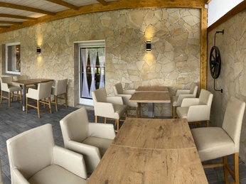 Überdachte Veranda mit gemauerten Wänden, Holzdach und bequemen Sitzgelegenheiten im Freien.