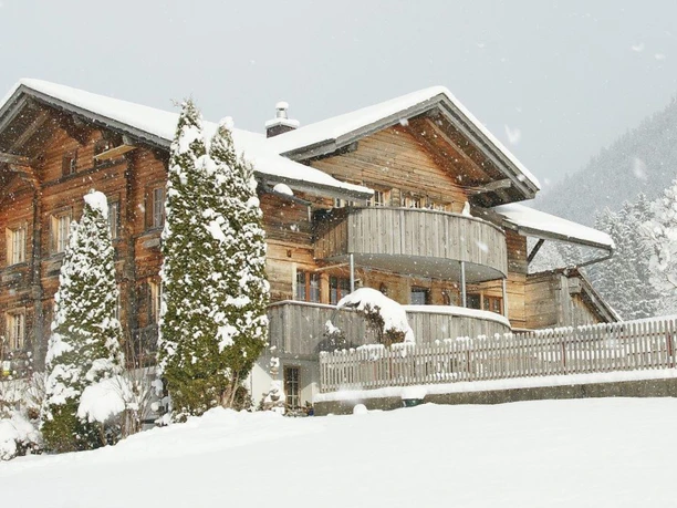 Mehrstöckiges Holzchalet in verschneiter Winterlandschaft