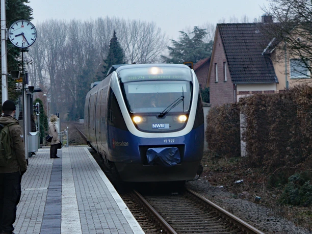 Ein moderner Zug der NordWestBahn erreicht den Bahnhof Schloß Neuhaus an einem bewölkten Tag.