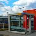 Ein kleiner Bahnhof mit moderner Wartehalle im Vordergrund, im Hintergrund ein NordWestBahn-Zug.