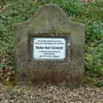 Gedenkstein für Reiter Kurt Schmidt, umgeben von Laub und Grün, in Waldnähe platziert.
