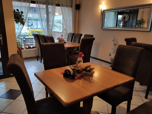 Im Vordergrund ein Tisch für 2 Personen mit Weihnachtsdecko, im Hintergrund ein größerer Tisch