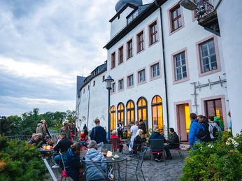 Schloss Wildenfels zur Nacht der Schlösser 2021 Menschen genießen den Abend vor Schloss Wildenfels mit beleuchteten Fenstern und wolkigem Himmel.People enjoy the evening in front of Wildenfels Castle with illuminated windows and a cloudy sky.Lidé si užívají večer před hradem Wildenfels s osvětlenými okny a zataženou oblohou.Ludzie cieszą się wieczorem przed zamkiem Wildenfels z oświetlonymi oknami i zachmurzonym niebem.Mensen genieten van de avond voor kasteel Wildenfels met verlichte ramen en een bewolkte hemel.La gente si gode la serata davanti al castello di Wildenfels con le finestre illuminate e il cielo nuvoloso.