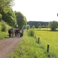 Ellerbachtal bei Paderborn-Dahl Eine Gruppe von Wanderern spaziert auf einem Naturweg im Ellerbachtal, umgeben von blühenden Wiesen.