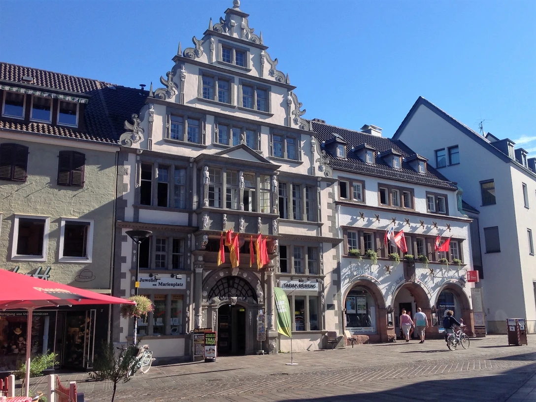 Historisches Fachwerkhaus mit reich verziertem Giebel, Sitz der Touristeninformation, umgeben von Geschäften.