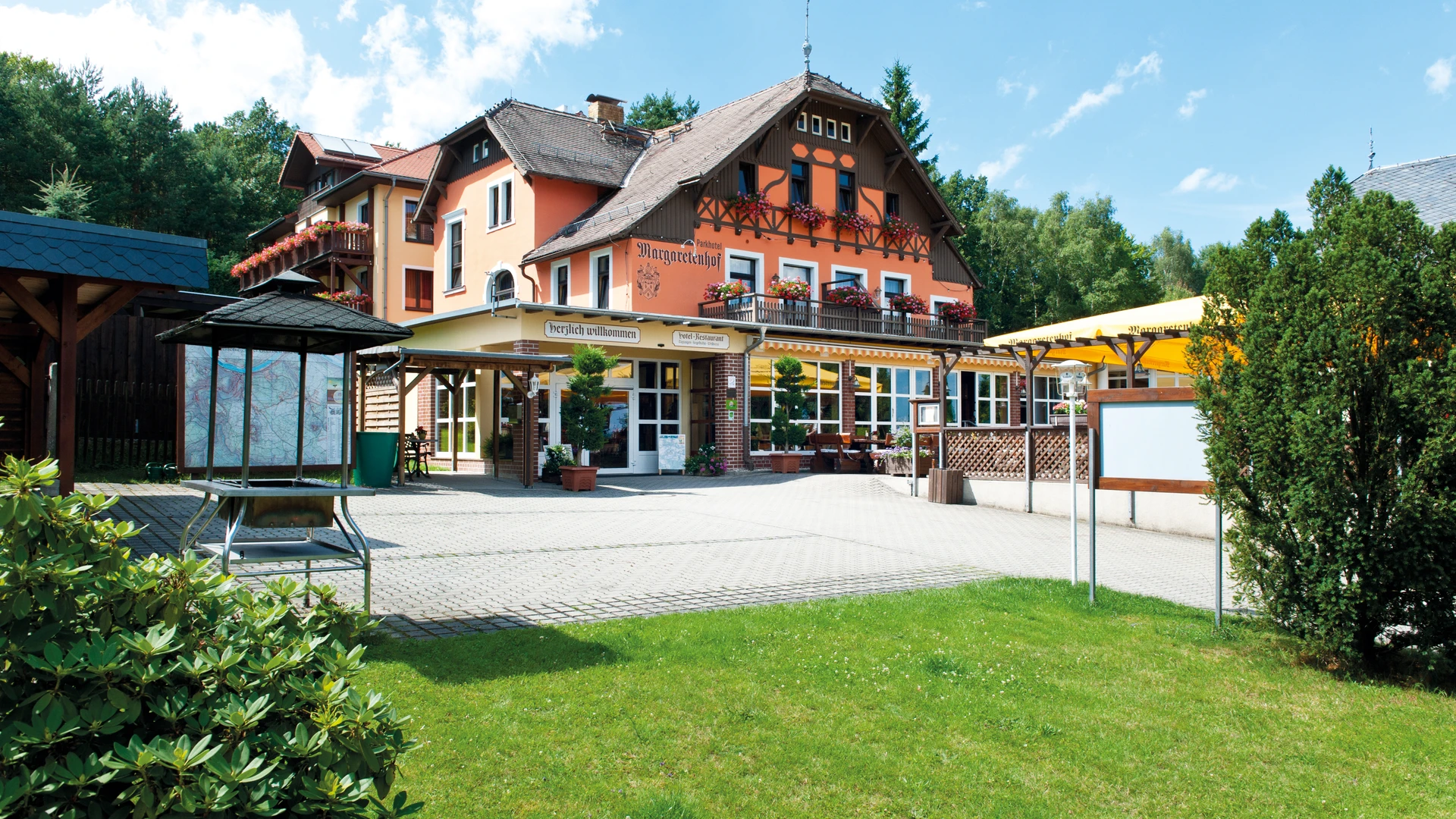 Fassade eines mehrstöckigen Gebäudes mit Balkonen, umgeben von Grünflächen und Bäumen.