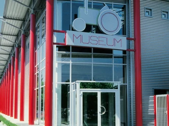 Deutsches Traktoren und Modellauto Museum, Eingang Eingang des Deutschen Traktoren und Modellauto Museums mit markant roten Säulen und Glasfassade.
