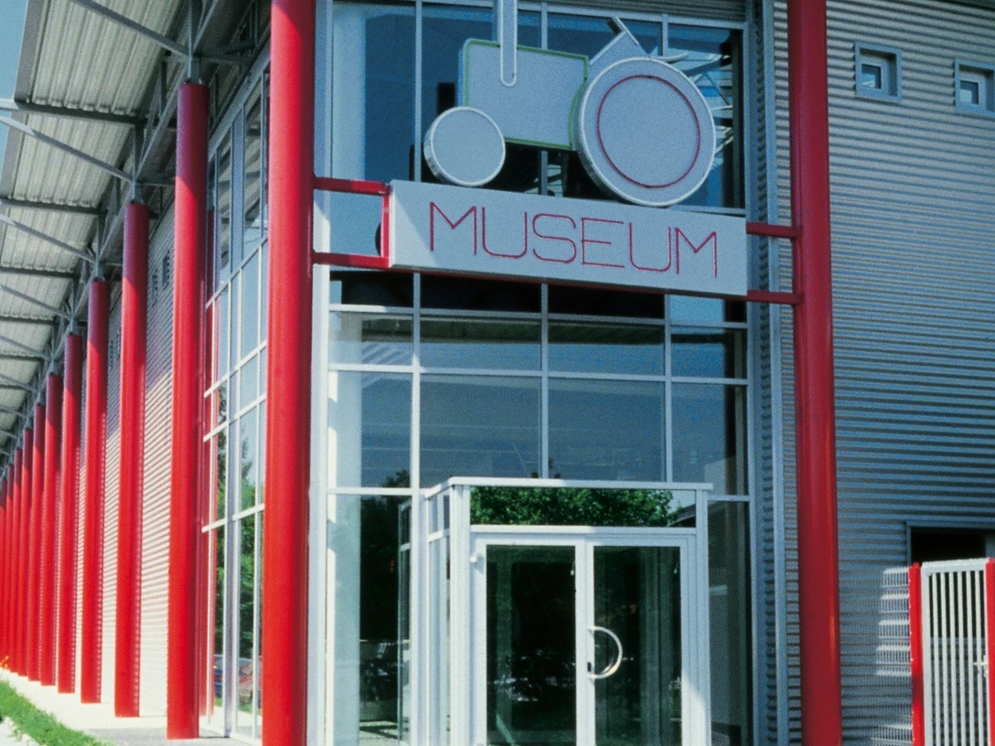 Deutsches Traktoren und Modellauto Museum, Eingang Eingang des Deutschen Traktoren und Modellauto Museums mit markant roten Säulen und Glasfassade.