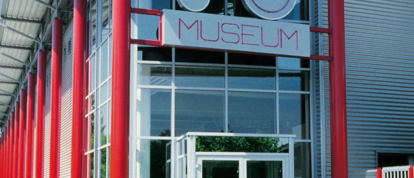 Deutsches Traktoren und Modellauto Museum, Eingang Eingang des Deutschen Traktoren und Modellauto Museums mit markant roten Säulen und Glasfassade.