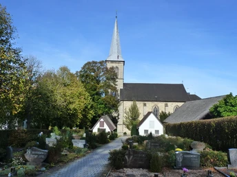 Pfarrkirche St. Margaretha und Friedhof in Dahl Pfarrkirche St. Margaretha in Dahl mit gravierten Grabsteinen, umgeben von Bäumen bei sonnigem Himmel.