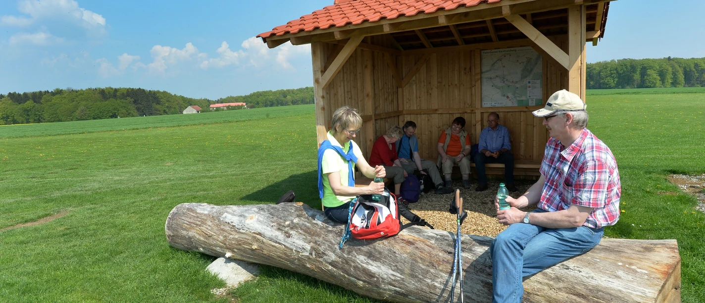 Schutzhütte auf dem Knipsberg mit Picknickbank, umgeben von Wiesen und Wäldern im Hintergrund.