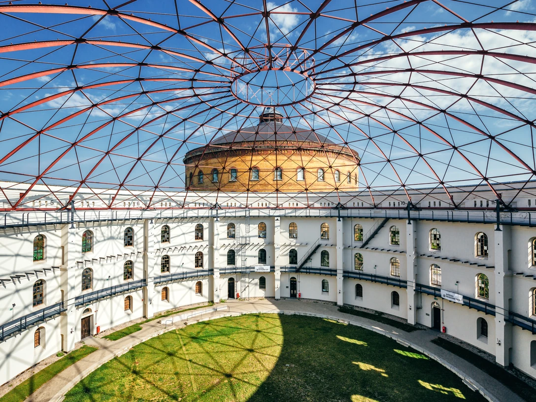 Aréna u Panometru v Lipsku – průmyslová kultura v Lipsku Blick in die Open Air Rotunde der Arena am Panometer, im Hintergrund das Panometer vor blauem Himmel, Industriekultur, Veranstaltungen, SehenswürdigkeitenRzut oka na rotundę areny przy Panometrze, na dalszym planie Panometr na tle błękitnego nieba, kultura przemysłowa, wydarzenia, zabytkiLooking into the open-air rotunda of the Panometer Arena with the Panometer in the background against a blue sky, industrial culture, events, sightseeingVue de la rotonde en plein air de l’Arena am Panometer, en arrière-plan le Panometer sur fond de ciel bleu, culture industrielle, événements, attractions touristiquesPohled na rotundu Arény u Panometru s její otevřenou střechou, v pozadí modrého nebe silueta Panometru, průmyslová kultura, akce, pozoruhodnosti