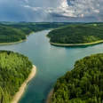 Wiehltalsperre aus der Luft Weite grüne Wälder umrahmen eine mäandernde Flusslandschaft unter einem eindrucksvollen Himmel.