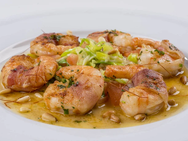 Albermann_5.jpg Gegrillte Garnelen mit Pinienkernen und Gemüse auf weißem Teller kunstvoll angerichtet.