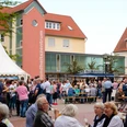 Weinfest Menschenmenge auf einem belebten Weinfest mit Zelten und umgebenden Gebäuden bei sonnigem Wetter.