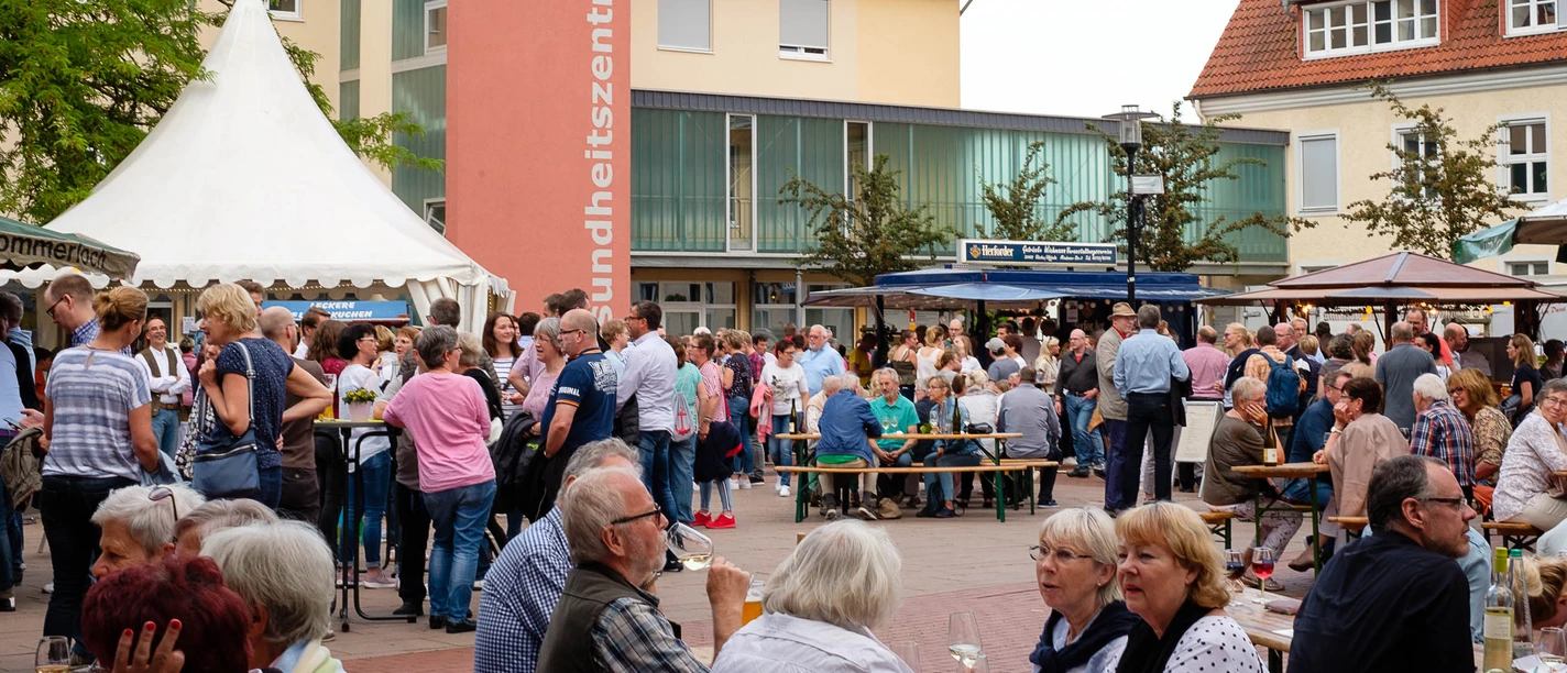 Weinfest Menschenmenge auf einem belebten Weinfest mit Zelten und umgebenden Gebäuden bei sonnigem Wetter.