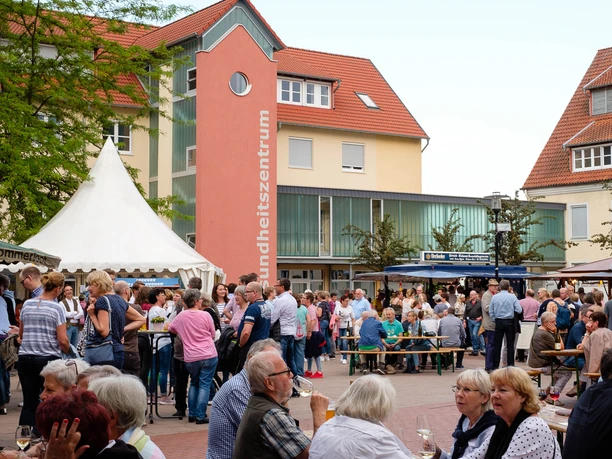 Weinfest Menschenmenge auf einem belebten Weinfest mit Zelten und umgebenden Gebäuden bei sonnigem Wetter.