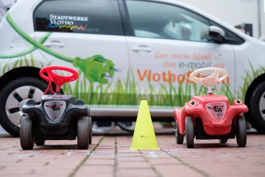 Bobby Car Vlotho fährt ab Links und rechts ein Bobby Car, in der Mitte eine Pylone, im Hintergrund ist ein VW-UP zu sehen