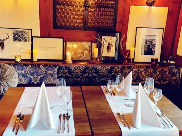 Zwei ansprechend gedeckte Tische in einem stimmungsvoll beleuchteten Restaurant mit Jagd-Dekorationen.