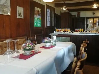 cafe-grosskopff-01.jpg Ein gemütliches, rustikales Restaurant mit gedeckten Tischen, Blumenarrangement und Holzmöbeln.