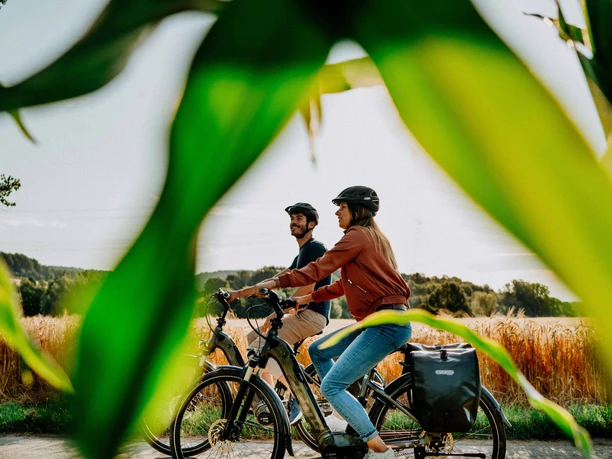Teutoburger Wald Zwei Radfahrer in sommerlicher Landschaft, umrahmt von grünem Blattwerk, im Teutoburger Wald.