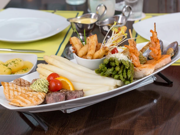 Ein großes, vielfältiges Spargelgericht mit gegrilltem Fleisch, Meeresfrüchten und knusprigen Beilagen.