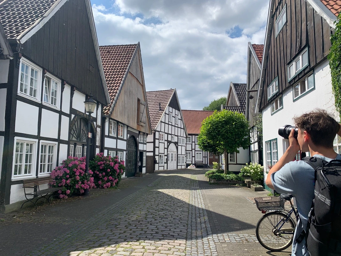 Ein malerisches Fachwerkdorf, ein Radfahrer hält an, um die idyllische Kulisse in Ruhe zu fotografieren.