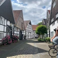 Ein malerisches Fachwerkdorf, ein Radfahrer hält an, um die idyllische Kulisse in Ruhe zu fotografieren.