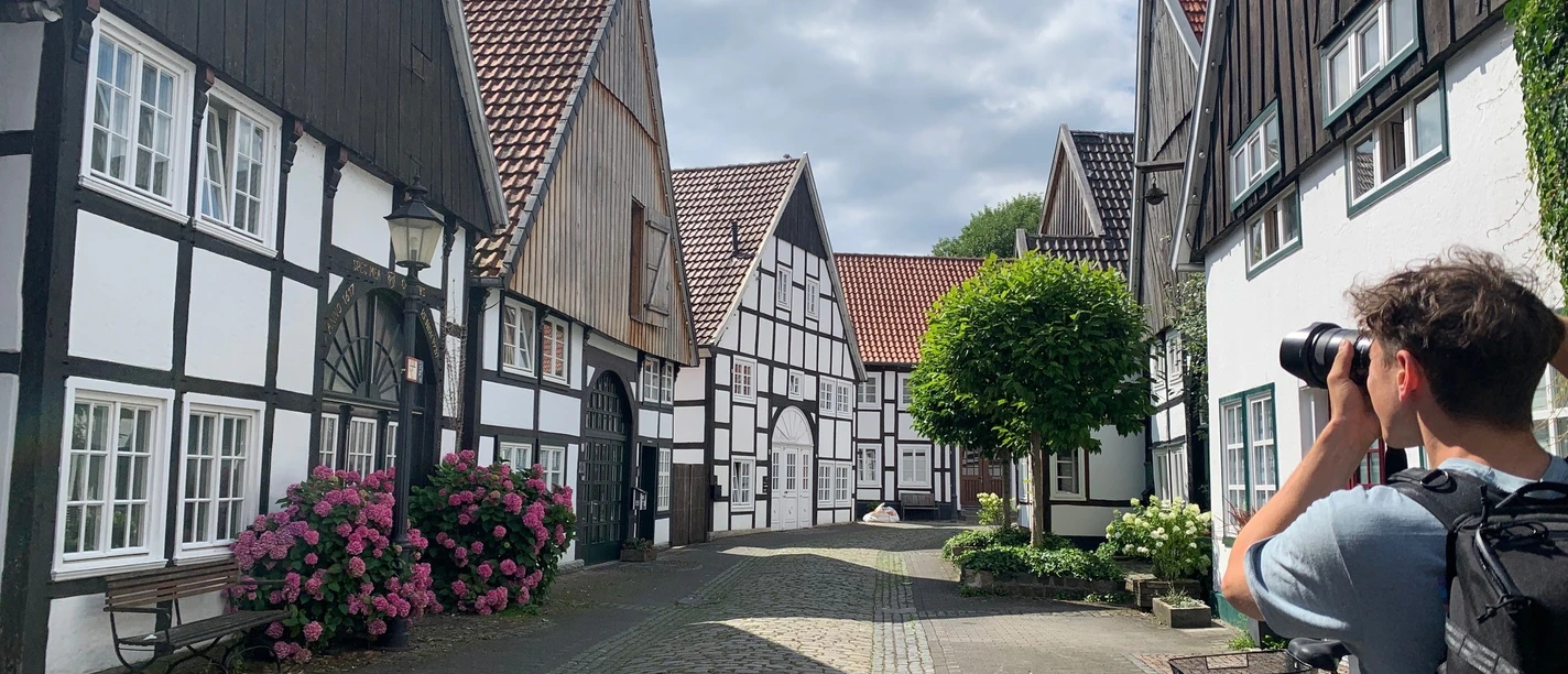 Altstadt Rheda Ein malerisches Fachwerkdorf, ein Radfahrer hält an, um die idyllische Kulisse in Ruhe zu fotografieren.