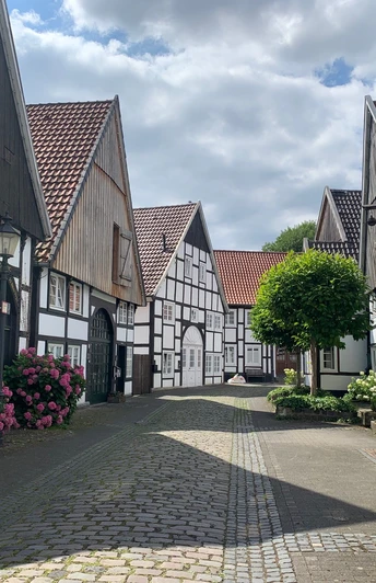 Altstadt Rheda Ein malerisches Fachwerkdorf, ein Radfahrer hält an, um die idyllische Kulisse in Ruhe zu fotografieren.